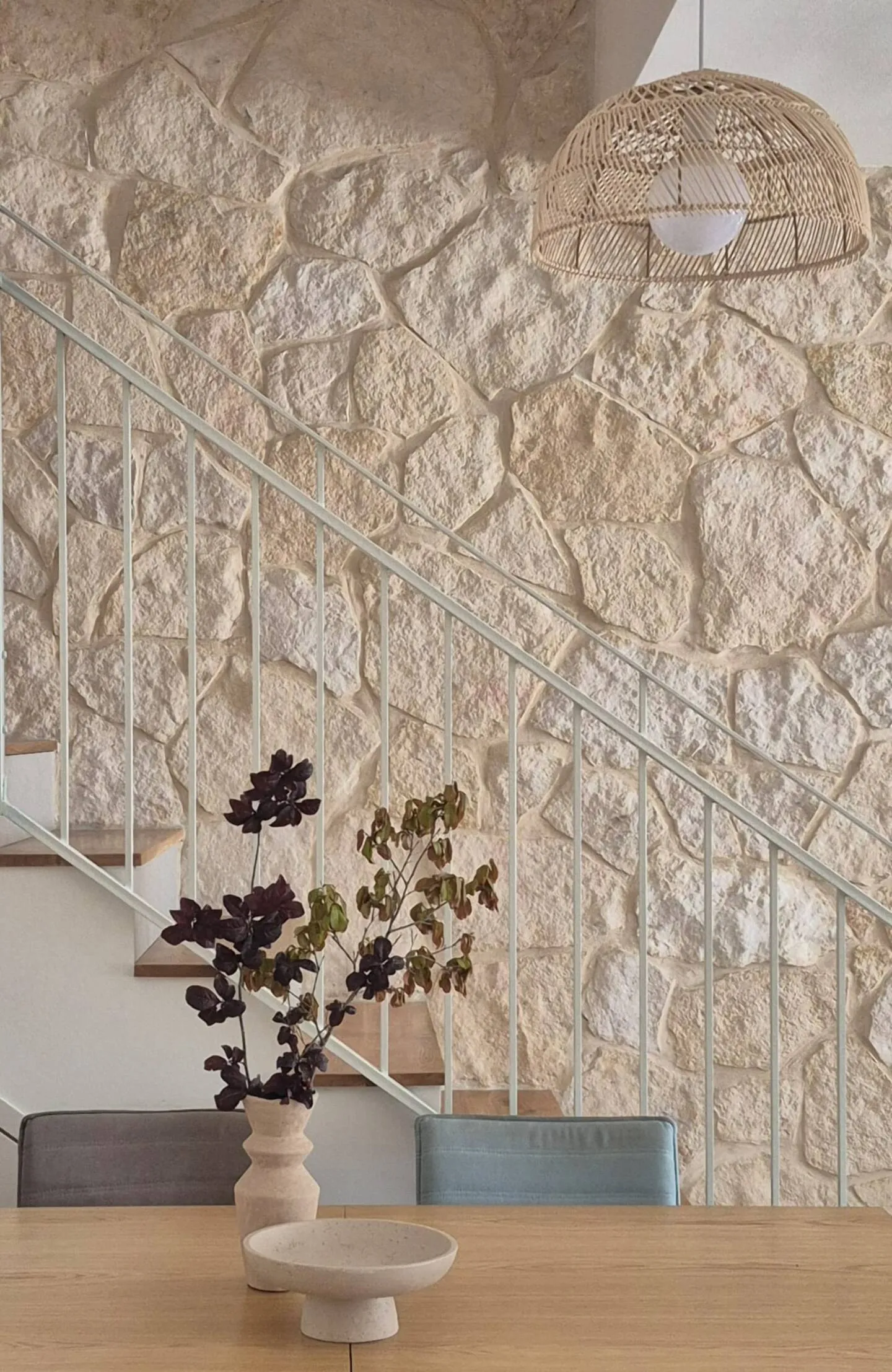Entry stair beside a stone feature wall, with a plant.