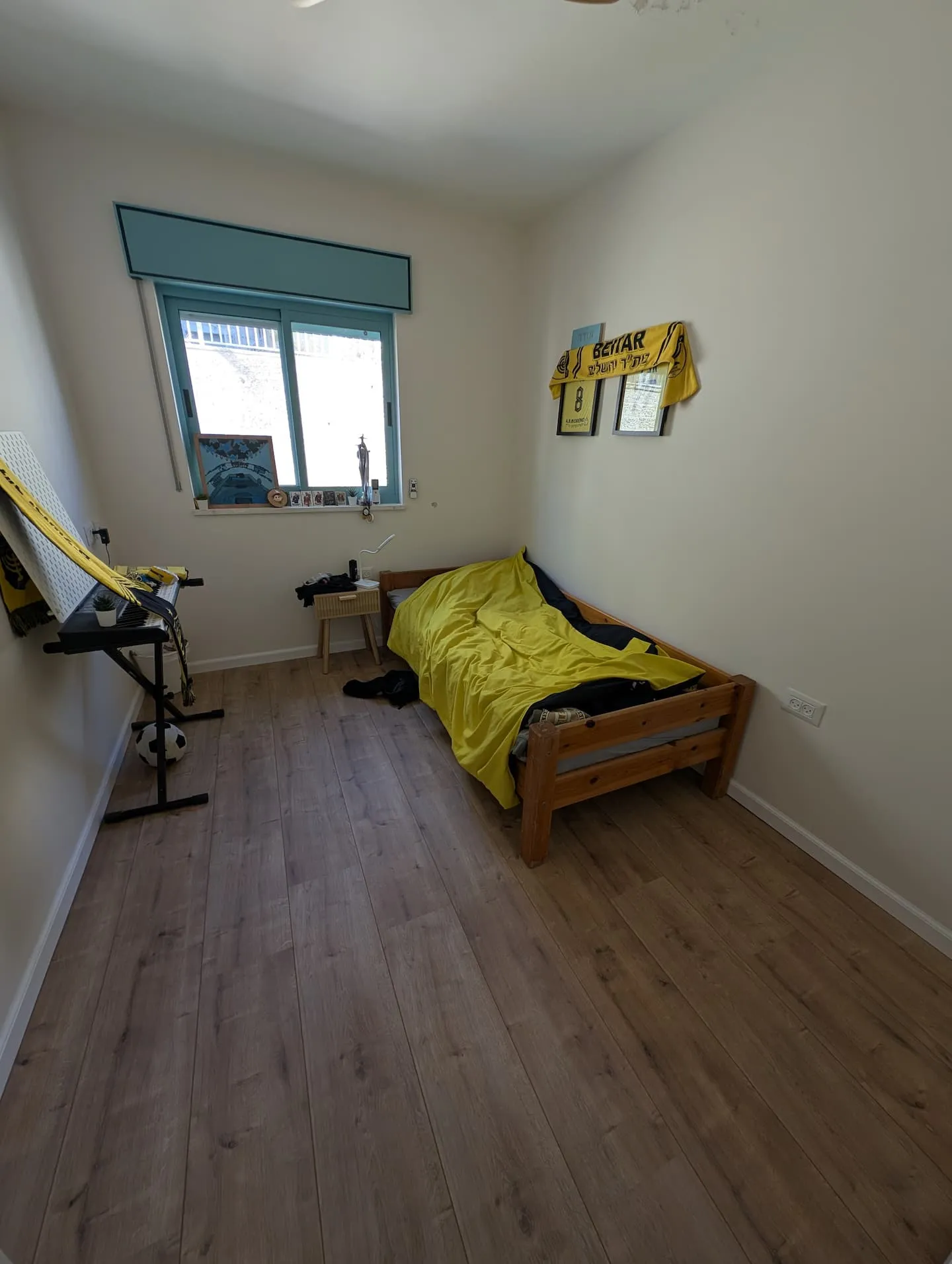 Bedroom with a single bed and yellow bedding. A stationary exercise bike is in the room.